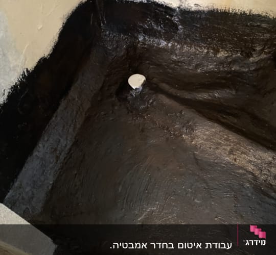 איטום רצפה עם חומר שחור סביב צינור ניקוז